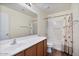Well-lit bathroom with a white countertop, wood cabinets, and a shower-tub combination at 2009 E Lindrick Dr, Gilbert, AZ 85298