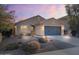 Inviting single-story home featuring neutral stucco, a two-car garage, desert landscaping, and an American flag at 2009 E Lindrick Dr, Gilbert, AZ 85298