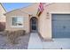 Close-up of a single-story home featuring neutral stucco, desert landscaping, and an American flag at 2009 E Lindrick Dr, Gilbert, AZ 85298