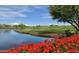 Scenic golf course view featuring a serene lake surrounded by lush greenery and vibrant red flowers in the foreground at 20100 N 78Th Pl # 2210, Scottsdale, AZ 85255