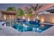 Backyard pool features a baja step, waterfall, and adjacent outdoor kitchen beneath a beautiful desert sunset at 20125 E Via Del Rancho --, Queen Creek, AZ 85142