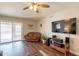 Comfortable living room with hardwood floors, a ceiling fan, media center, and sliding glass doors to backyard at 2359 W Del Oro Cir, Mesa, AZ 85202