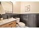 Stylish powder room features a wood-look vanity, a black framed mirror, wainscoting, and decorative tile floors at 25945 W Sands Dr, Buckeye, AZ 85396