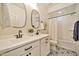 Bathroom features double sinks, oval mirrors, patterned tile floor, and a shower-tub combination at 25945 W Sands Dr, Buckeye, AZ 85396