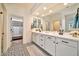 Bright bathroom boasts double sinks, patterned tile flooring, and access to a walk-in closet with custom shelving at 25945 W Sands Dr, Buckeye, AZ 85396