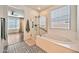 Bright bathroom with a soaking tub, glass enclosed shower, patterned tile floors, and a view to the bedroom at 25945 W Sands Dr, Buckeye, AZ 85396