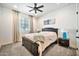 Bedroom with gray carpet, ceiling fan, and art piece above the dark wood headboard at 25945 W Sands Dr, Buckeye, AZ 85396