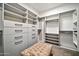 Walk-in closet with custom shelving, drawers, and a tufted bench for organized storage and a touch of luxury at 25945 W Sands Dr, Buckeye, AZ 85396