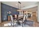 Dining room with a dark wood table, neutral upholstered chairs, a modern chandelier, and an accent wall at 25945 W Sands Dr, Buckeye, AZ 85396