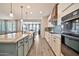 Open kitchen with a center island, farmhouse sink, pendant lights, and stainless steel appliances, open to dining room at 25945 W Sands Dr, Buckeye, AZ 85396