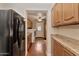 Hallway featuring abundant wood cabinets, tile countertops, black refrigerator, and a laundry area at 576 W Moon Valley Dr, Phoenix, AZ 85023