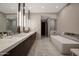 Modern bathroom featuring dual sinks with marble counters, sleek cabinets, and a luxurious soaking tub at 5935 N Echo Canyon Ln, Phoenix, AZ 85018