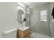 Modern bathroom features a glass shower, sleek vanity with a gold-trimmed oval mirror, and gray tiles at 829 W Mitchell Dr, Phoenix, AZ 85013