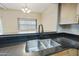 Close-up of a modern kitchen sink with black granite countertops and a view into the dining area at 8614 N 67Th Dr, Peoria, AZ 85345