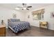 Bright bedroom with wood-look floors, ceiling fan, large bed, window, and charming decor at 10439 W Saratoga Cir, Sun City, AZ 85351