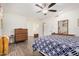 Bright bedroom featuring wood-look floors, ceiling fan, large dresser and bed with patterned blue bedding at 10439 W Saratoga Cir, Sun City, AZ 85351