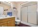 Bathroom features a sink with oak colored cabinets and a shower with glass doors at 10718 W Welk Dr, Sun City, AZ 85373