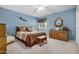 Cozy bedroom featuring blue walls, soft carpet, and a decorative wooden dresser with a quaint mirror at 10718 W Welk Dr, Sun City, AZ 85373