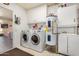 Functional laundry room featuring a washer, dryer, water heater, and sink with storage at 10718 W Welk Dr, Sun City, AZ 85373