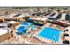 Aerial view of a large swimming pool complex featuring various pools, shaded seating, and surrounding lush landscaping at 10718 W Welk Dr, Sun City, AZ 85373