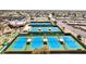 Aerial view of tennis courts, with clear blue surfaces, surrounded by lush greenery and mature trees at 10718 W Welk Dr, Sun City, AZ 85373