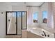 Modern bathroom showcases a glass-enclosed shower and a corner jacuzzi tub near two windows at 1233 E Azure Sea Ln, Gilbert, AZ 85234