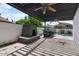 This outdoor living space has a fireplace, an outdoor kitchen with seating, and an elegant ceiling fan at 1233 E Azure Sea Ln, Gilbert, AZ 85234