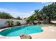 A serene pool surrounded by palm trees, plants, and rock features offering a relaxing backyard oasis at 1233 E Azure Sea Ln, Gilbert, AZ 85234