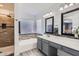 Bright bathroom with double mirrors and a shower over tub with decorative tile at 13444 W Ocotillo Ln, Surprise, AZ 85374