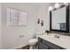 Well-lit half-bath with gray vanity, decorative mirror, and a window that provides natural light at 13444 W Ocotillo Ln, Surprise, AZ 85374