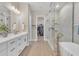 Bright main bathroom with double vanity, stand alone tub, glass shower and walk-in closet at 1356 E Penedes Ct, Gilbert, AZ 85298