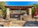 Covered outdoor kitchen with stone accents, dining area, and built-in grill, perfect for al fresco dining and entertaining at 1412 E Jade Dr, Chandler, AZ 85286