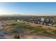 Expansive aerial view of a residential community bordering a golf course, with mountain views in the distance at 14257 W Harvard St, Goodyear, AZ 85395