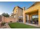 A backyard area of the house featuring a patio, table, a wall, well-maintained grass, and greenery at 14257 W Harvard St, Goodyear, AZ 85395