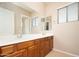 Bathroom featuring double sinks, wood cabinets, a large mirror, and a bright, window-filled space at 14257 W Harvard St, Goodyear, AZ 85395