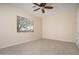 A bright bedroom features a window, ceiling fan and neutral carpet and paint at 14257 W Harvard St, Goodyear, AZ 85395