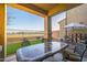 A covered patio with dark outdoor furniture and a view of a well-manicured green lawn at 14257 W Harvard St, Goodyear, AZ 85395