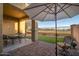 Covered patio with an umbrella table and a view of the lawn and golf course in the background at 14257 W Harvard St, Goodyear, AZ 85395