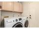 Laundry room featuring modern white washer and dryer appliances with upper cabinets at 15618 N 12Th Ave, Phoenix, AZ 85023