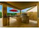An outdoor kitchen featuring a large grill, bar seating area, covered patio, and red umbrella at 15618 N 12Th Ave, Phoenix, AZ 85023
