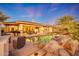 Beautiful backyard featuring a rock waterfall cascading into a pool with ample seating and a covered patio at 18059 W Ocotillo Ave, Goodyear, AZ 85338