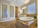 Spa-like bathroom with a soaking tub, tile flooring, glass block accents, and soft lighting at 18059 W Ocotillo Ave, Goodyear, AZ 85338