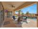 Covered patio with outdoor seating offers a great view of the pool with rock waterfall and palm trees at 18059 W Ocotillo Ave, Goodyear, AZ 85338