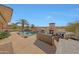 Beautiful pool area featuring a rock waterfall, palm trees, outdoor fireplace, and grill, perfect for entertaining guests at 18059 W Ocotillo Ave, Goodyear, AZ 85338