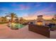 Inviting backyard pool with a rock waterfall, palm trees, and a cozy outdoor fireplace with comfortable seating at 18059 W Ocotillo Ave, Goodyear, AZ 85338