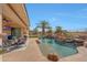 Inviting pool with rock waterfall feature and lush landscaping, complemented by an adjacent covered patio with comfortable seating at 18059 W Ocotillo Ave, Goodyear, AZ 85338