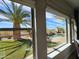 Palm tree, turf, pool and outdoor kitchen seen through a well-lit picture window at 18059 W Ocotillo Ave, Goodyear, AZ 85338