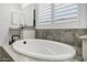 A soaking tub in a bathroom with white cabinets and granite counters at 20125 E Melissa Pl, Queen Creek, AZ 85142