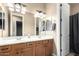 Well-lit bathroom featuring a double vanity, wood cabinets, a framed mirror and a shower with gray curtain at 2089 E Lynx Pl, Chandler, AZ 85249