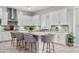 Bright kitchen with white cabinetry, mosaic backsplash, granite countertops and island with seating for five at 20981 E Watford Dr, Queen Creek, AZ 85142